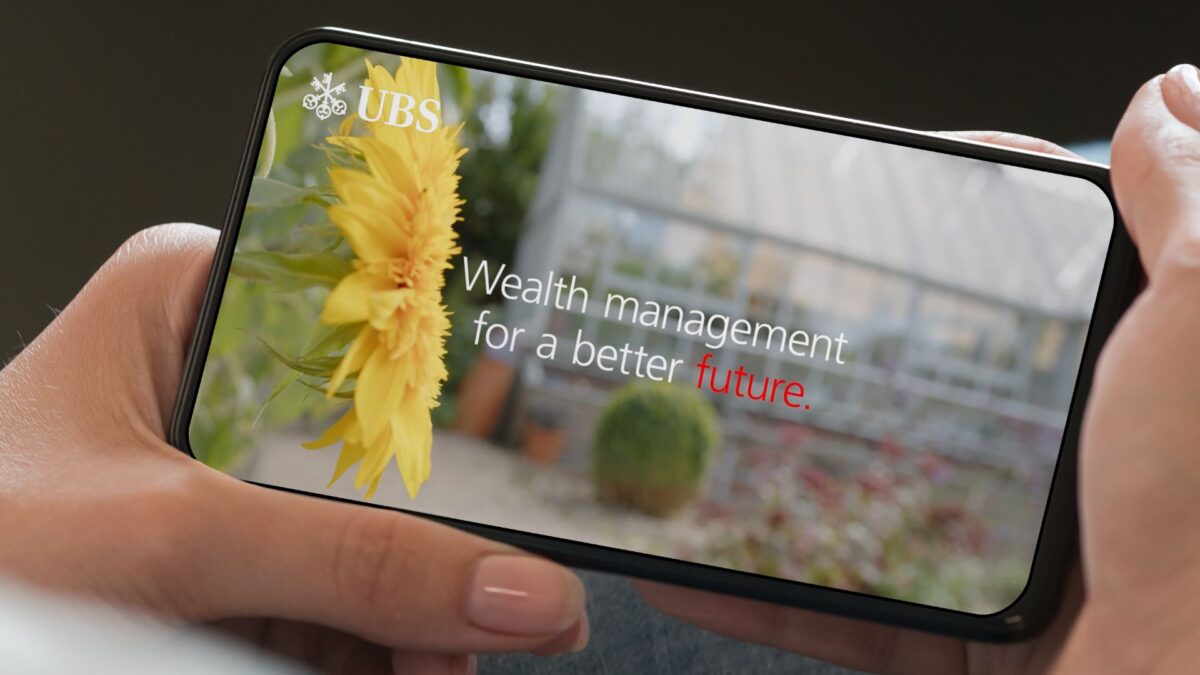 An image of UBS's sustainability video on a phone number being held by someone.