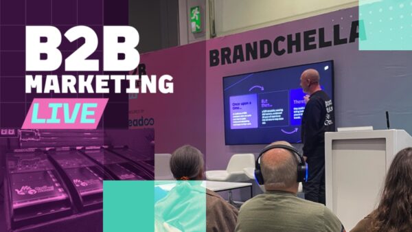 Man delivering speech to a group of people at a B2b Marketing conference with the headline 